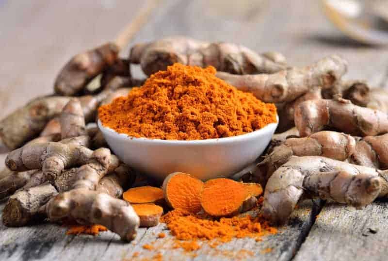 turmeric powder in white dish on wooden background, care management for achilles tendon injuries