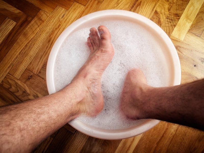 Man soaking his feet in a washbowl.