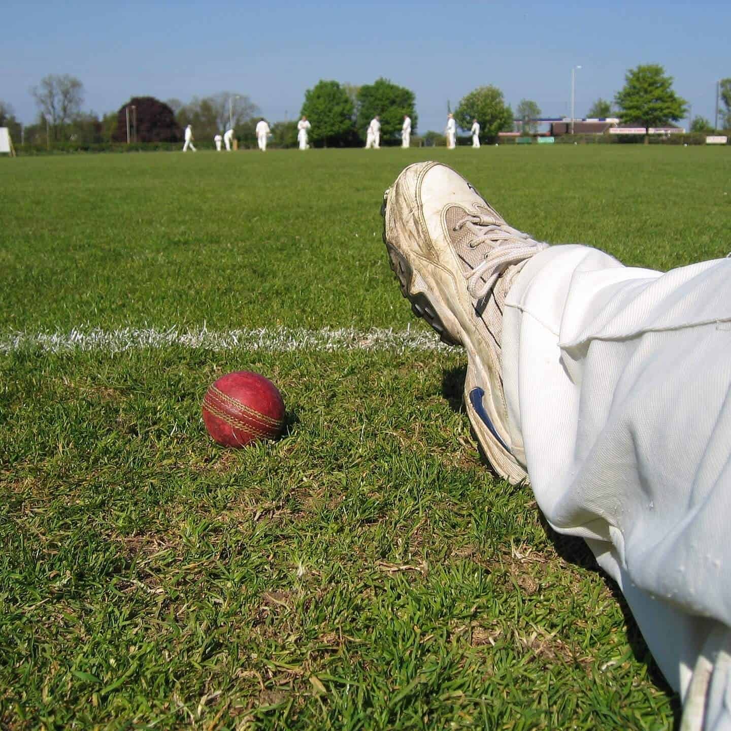 A Cricket Player sitting at one corner with a ball beside him
