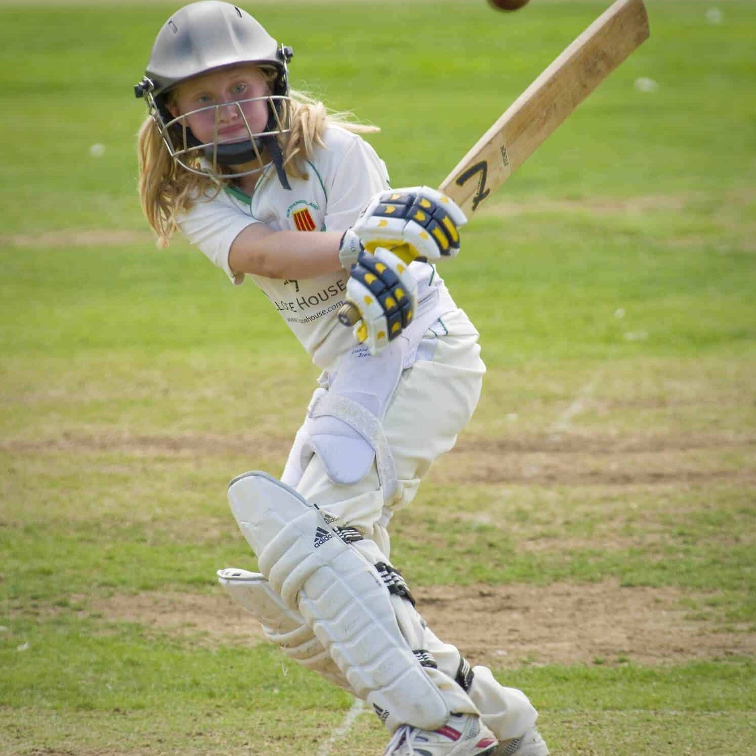 A Cricket Player hitting the ball with her bat